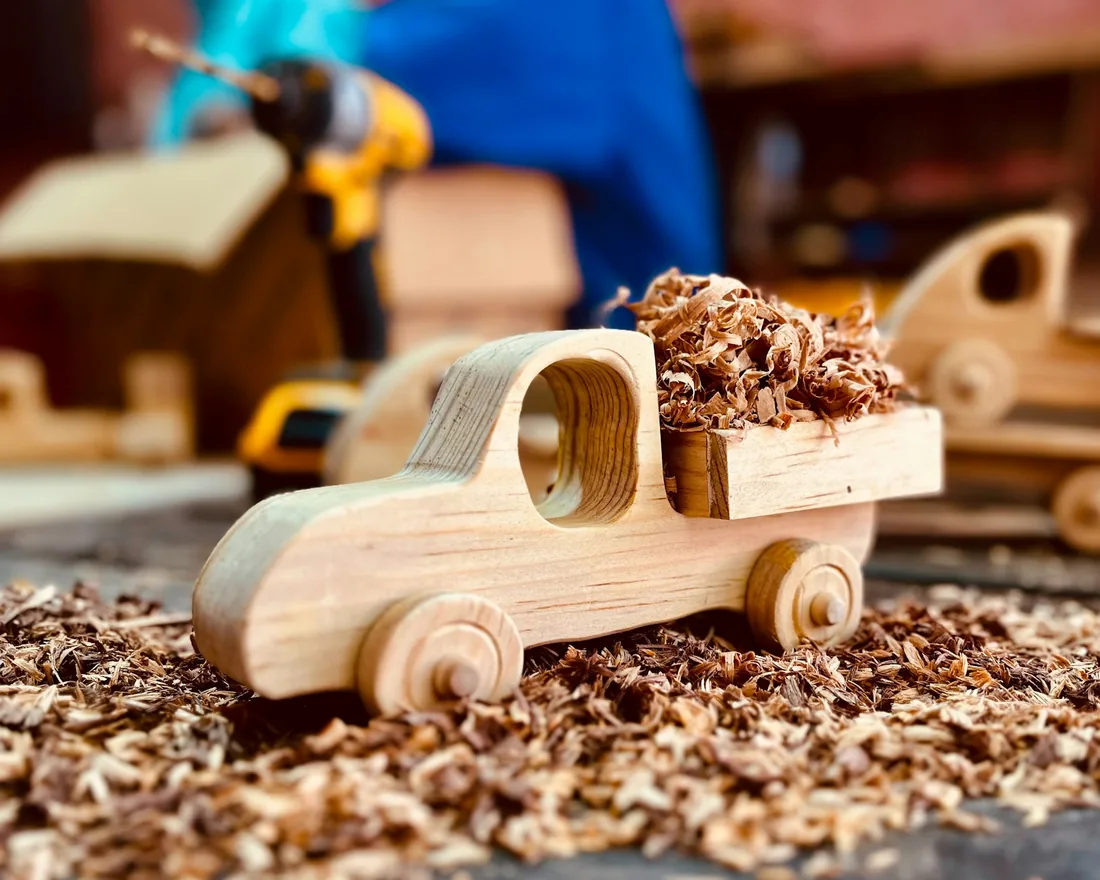 Camión de juguete de madera sin barnizar sobre virutas, en la mesa de un taller